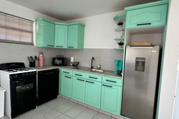 Fully equipped kitchen at Villa Sunset in Aruba with aqua cabinets, stainless steel fridge, stove, dishwasher, and Keurig coffee maker.