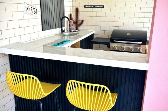 Colorful private bar with BBQ grill, sink, and seating at Villa Sunset in Aruba, an adults-only vacation rental designed for couples.