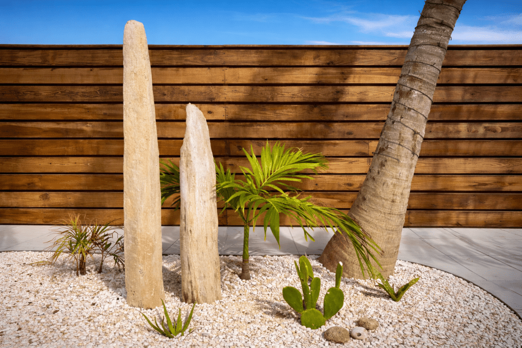 flamingo-bay-villas-aruba-tropical-garden-landscaping Tropical garden landscaping at Flamingo Bay Villas in Aruba with palm trees, coral stone pillars and white gravel courtyard.