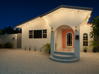 Villa Sunrise at Flamingo Bay Villas in Aruba lit up at night with white stucco walls and tropical landscaping.