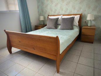 Cozy bedroom at Villa Sunrise in Aruba with wooden sleigh bed, aqua accents, and tropical wallpaper—perfect for couples on an adults-only escape