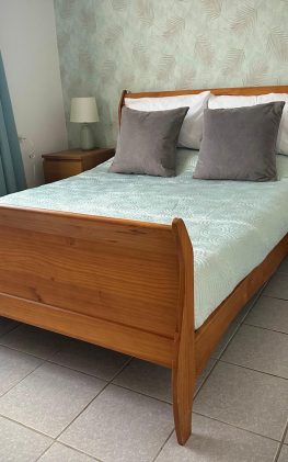 Cozy bedroom at Villa Sunrise in Aruba with wooden sleigh bed, aqua accents, and tropical wallpaper—perfect for couples on an adults-only escape