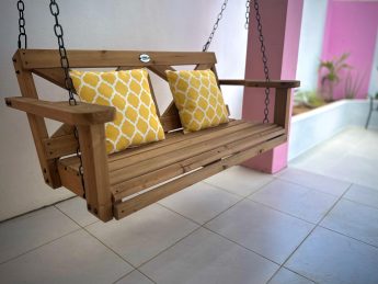 Wooden porch swing with yellow cushions at Villa Sunrise, Flamingo Bay Villas Aruba.