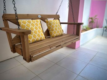 Wooden porch swing with yellow cushions at Villa Sunrise, Flamingo Bay Villas Aruba.