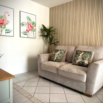 Living room with sofa, tropical cushions, and flamingo wall art at Villa Sunrise, Flamingo Bay Villas Aruba.