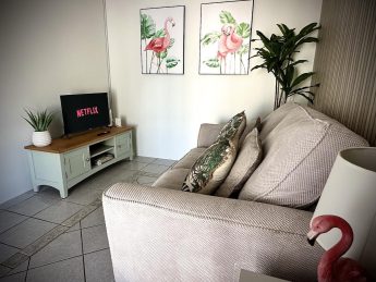Living room with sofa, tropical cushions, and flamingo wall art at Villa Sunrise, Flamingo Bay Villas Aruba.