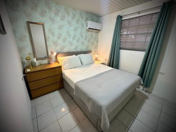 Bedroom with queen bed, accent wall, and modern decor at Villa Sunrise, Flamingo Bay Villas Aruba.