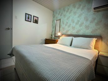 Bedroom with queen bed, accent wall, and modern decor at Villa Sunrise, Flamingo Bay Villas Aruba.
