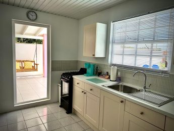 Fully equipped kitchen at Villa Sunrise, Flamingo Bay Villas Aruba with cabinets, sink, stove, microwave, and Keurig coffee maker.