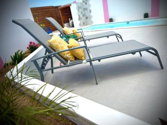Poolside loungers with yellow cushions at Villa Sunrise, Flamingo Bay Villas in Aruba.