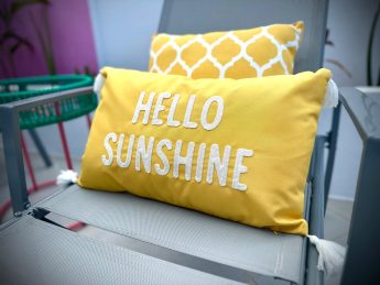 Close-up of yellow ‘Hello Sunshine’ cushion on a poolside chair at Villa Sunrise, Flamingo Bay Villas Aruba.