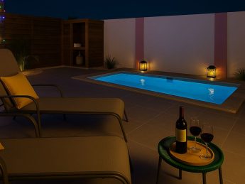 Private plunge pool lit at night with lanterns, lounge chairs, and wine at Flamingo Bay Villas Aruba.