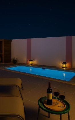 Private plunge pool lit at night with lanterns, lounge chairs, and wine at Flamingo Bay Villas Aruba.