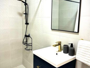 Contemporary bathroom at Villa Sunset in Aruba featuring a walk-in shower, elegant vanity with gold fixtures, and minimalist décor.