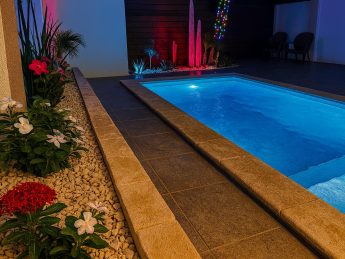 Luxury private pool at Villa Sunset in Aruba illuminated at night with tropical garden lighting, perfect for couples on an adults-only getaway.
