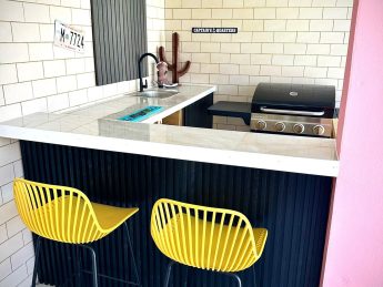 Colorful private bar with BBQ grill, sink, and seating at Villa Sunset in Aruba, an adults-only vacation rental designed for couples.