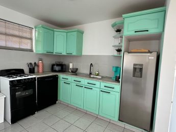 Fully equipped kitchen at Villa Sunset in Aruba with aqua cabinets, stainless steel fridge, stove, dishwasher, and Keurig coffee maker.